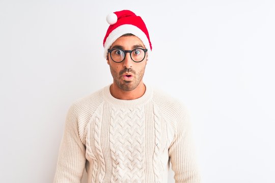 Young handsome man wearing christmas hat and glasses over isolated background afraid and shocked with surprise expression, fear and excited face.