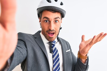 Young handsome business man wearing bike helmet taking a selfie over isolated background very happy and excited, winner expression celebrating victory screaming with big smile and raised hands
