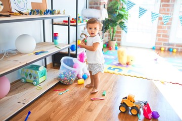 Adorable toddler playing around lots of toys at kindergarten