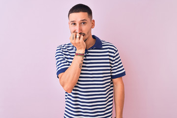 Fototapeta na wymiar Young handsome man wearing nautical striped t-shirt over pink isolated background looking stressed and nervous with hands on mouth biting nails. Anxiety problem.