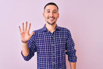 Naklejka premium Young handsome man standing over isolated background showing and pointing up with fingers number five while smiling confident and happy.