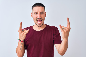 Fototapeta premium Young handsome man standing over isolated background shouting with crazy expression doing rock symbol with hands up. Music star. Heavy concept.