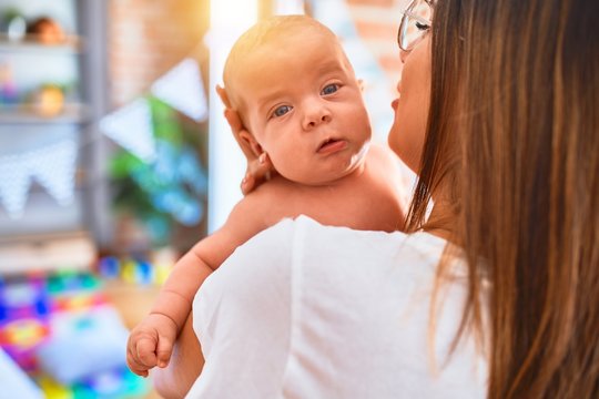 Young beautifull woman and her baby standing at home. Mother holding and hugging newborn