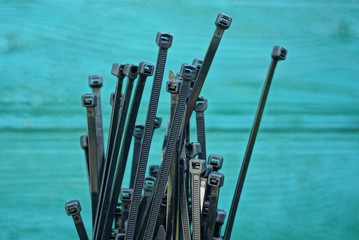 set of black long plastic ties on a green background