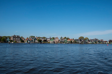 Naklejka na ściany i meble Zaanse Schans, Netherlands - 1 October 2019: Tourists sightseeng traditional Dutch rural houses in Zaanse Schans, is a typical small village within Amsterdam area.