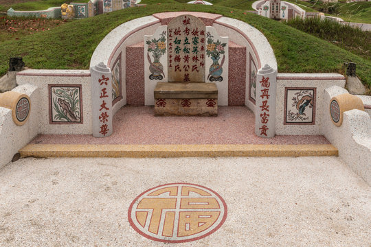 Bang Phra, Thailand - March 16, 2019: Chao Pho Khao Chalak Chinese Cemetery. Fish, flowers and synbol as decoration of beige-red family grave tombstone.