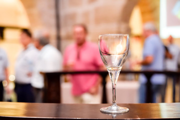 An empty wine glass on a wooden table during an event, with negative space