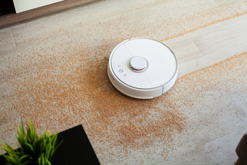 Robot vacuum cleaner performs automatic cleaning of the apartment at a certain time. Smart home.