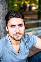 Close-up of a handsome young man model looks straight in front of the camera on a sunset