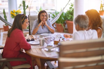 Young beautiful girl smiling happy and confident sitting dinking cup of coffee at terrace