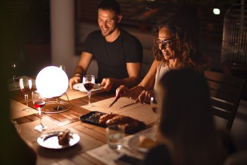 Beautiful family on dinner talking and smiling at terrace