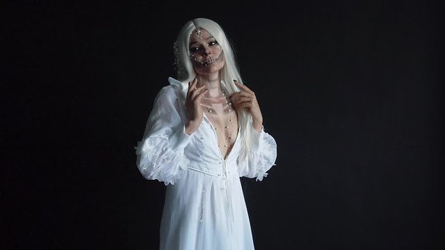 lady in vintage dress with deep neckline, adult attractive slender woman with creative make-up for deceased bride standing in black room, model with white hair as symbol of dead soul, working process