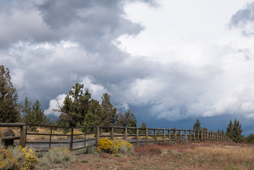 Western landscape with road,  old wood fence  and cloudy sky