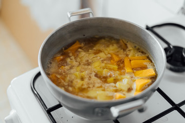 Pumpkin soup cooking in sausepan in the kitchen on the stove. Autumn traditional food