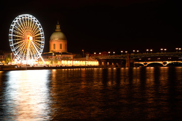 Naklejka premium Vue de nuit sur le fleuve, sa grande roue et le Dôme cuivré de la Grave, Toulouse
