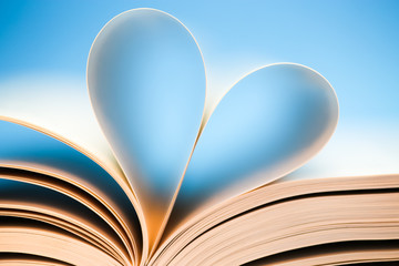 Book pages on blue background, glowing heart formed by book