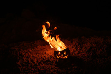 Tongues of flame in a pumpkin. jack-o-lantern on fire on a black background. Halloween symbol on the ground. Trick or treat. Close up.