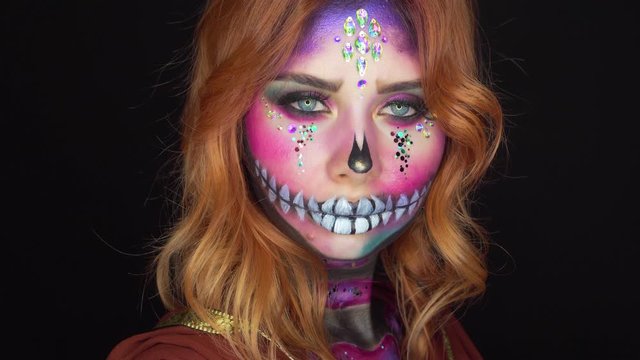 attractive girl with red fiery hair in dark room, image for Halloween and Day of Dead, bright creative style of sugar skull with pink and purple colors, excellent professional work of makeup artist