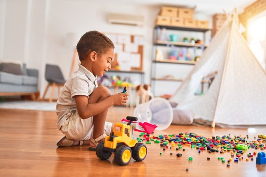 Beautiful african american toddler playing with small building blocks smiling at kindergarten