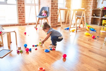 Beautiful toddler playing with train building with wooden blocks  at kindergarten