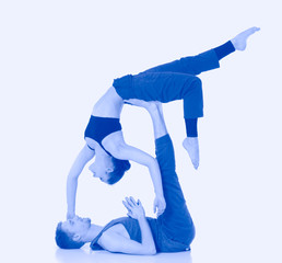 Young athletic couple practicing acroyoga. Balancing in pair.