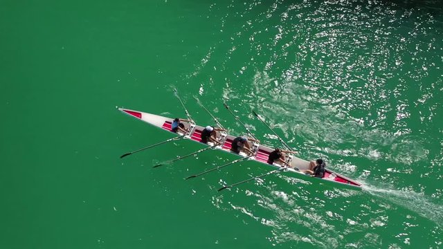 Aerial drone bird's eye view video of sport canoe operated by team of young women in emerald clear sea