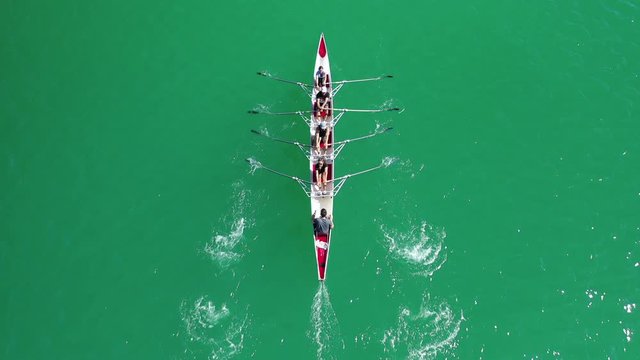 Aerial drone bird's eye view video of sport canoe operated by team of young women in emerald clear sea