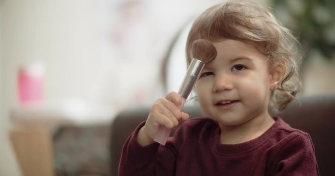 Cute baby girl playing with mom's makeup brushes. Shot in 4K RAW on a cinema camera.