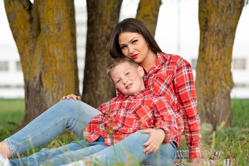 Mom and son sitting on the bedspread hugging.