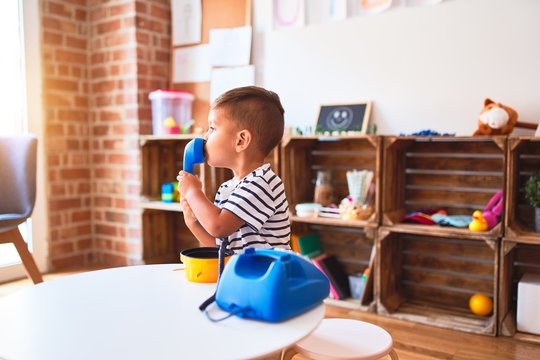 Beautiful toddler boy playing with vintage blue phone at kindergarten