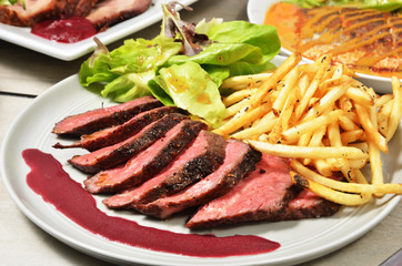 Roasted beef with french fries and salad on white plate 