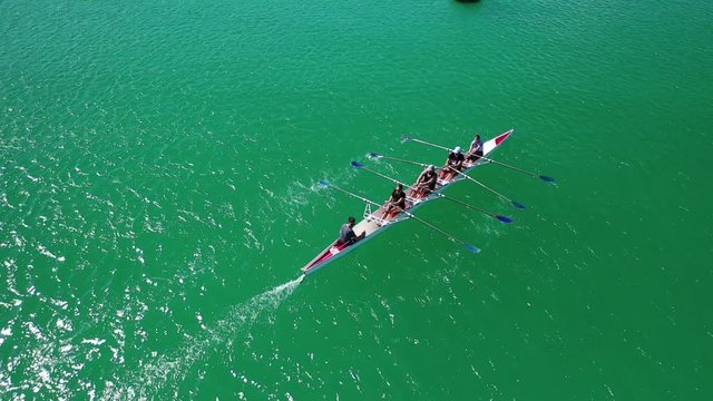 Aerial drone bird's eye view video of sport canoe operated by team of young women in emerald clear sea
