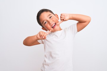 Beautiful kid boy wearing casual t-shirt standing over isolated white background smiling cheerful showing and pointing with fingers teeth and mouth. Dental health concept.