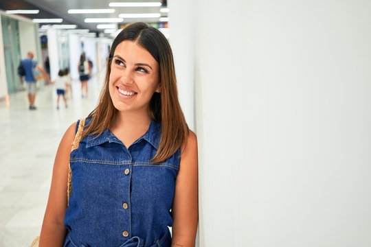 Young traveller woman at the airport going on vacation leaning on the wall