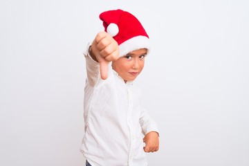 Beautiful kid boy wearing Christmas Santa hat standing over isolated white background looking unhappy and angry showing rejection and negative with thumbs down gesture. Bad expression.