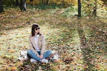 Young girl listening to music with headphones in the autumn forest. The girl is in a great mood and happy