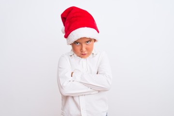 Beautiful kid boy wearing Christmas Santa hat standing over isolated white background skeptic and nervous, disapproving expression on face with crossed arms. Negative person.