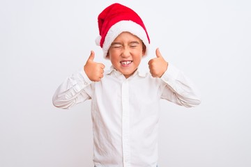 Beautiful kid boy wearing Christmas Santa hat standing over isolated white background excited for success with arms raised and eyes closed celebrating victory smiling. Winner concept.