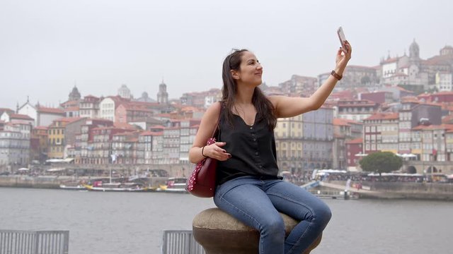 Young woman takes selfies in the city of Porto in Portugal - travel photography