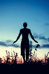 silhouette of a man standing in a yoga pose at sunset