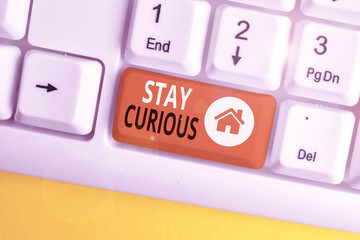 Conceptual hand writing showing Stay Curious. Concept meaning attention through being inexplicable or highly unusual White pc keyboard with note paper above the white background