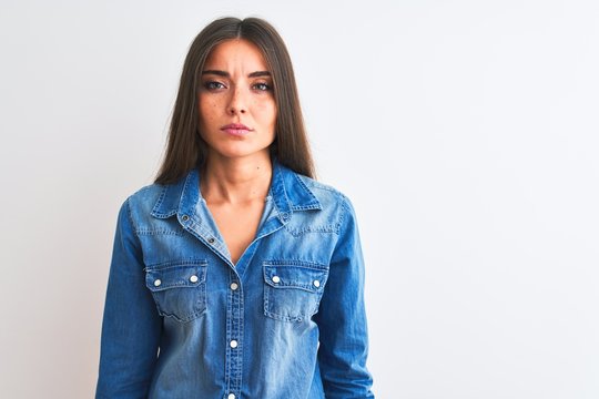 Young beautiful woman wearing casual denim shirt standing over isolated white background Relaxed with serious expression on face. Simple and natural looking at the camera.
