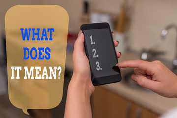 Writing note showing What Does It Mean Question. Business concept for Give me the meaning of something Definition woman using smartphone and technological devices inside the home