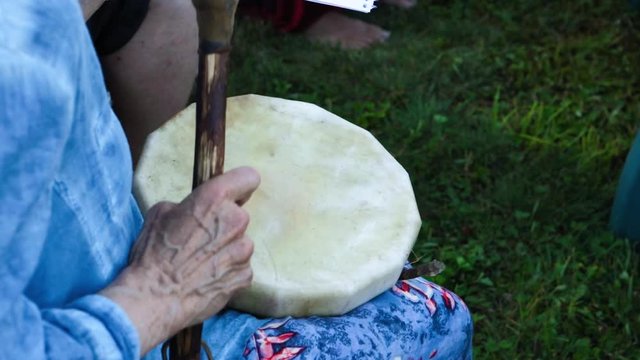 Sacred Drums At Spiritual Singing Group. An Older And Mature Woman Is Seen Experiencing Shamanic And Indigenous Culture During A Pow-wow Gathering At A Local Park, Playing A Small Handicraft Drum.