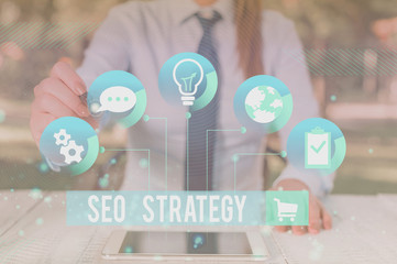 Writing note showing Seo Strategy. Business concept for procedures that aim to increase the visibility of a website Female human wear formal work suit presenting smart device