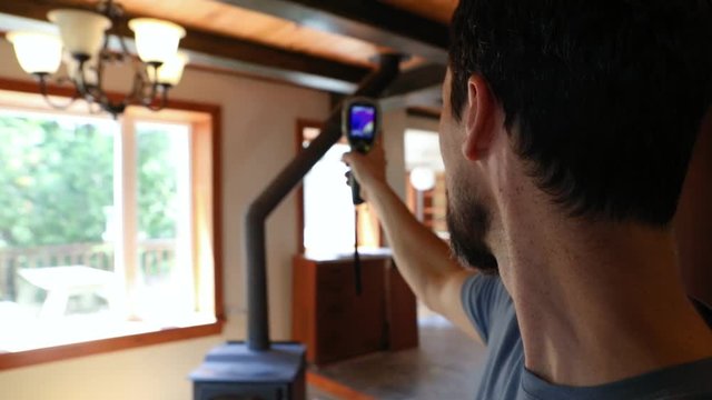 Indoor damp & air quality (IAQ) testing. Slow motion footage of a domestic building surveyor using a handheld infra red thermal imaging camera during an indoor environmental quality (IEQ) assessment.