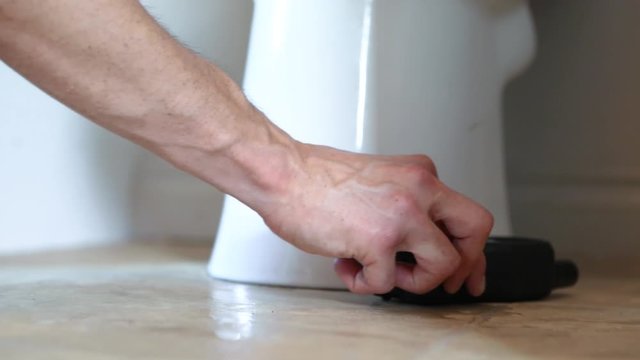 Indoor damp & air quality (IAQ) testing. Closeup footage of an environmental quality inspector using a small digital device around the base of a ceramic toilet pan during a domestic living assessment.