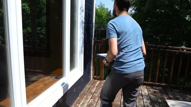 Indoor damp & air quality (IAQ) testing. Closeup and slow motion footage of a tall caucasian man at work, checking the door and window frames of a residential property against building regulations.