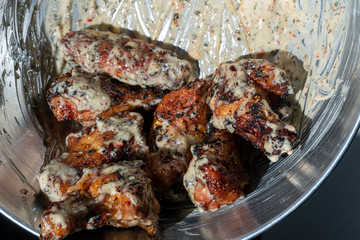 buffalo wings getting dressed with a sauce in a pan