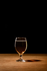 glass of beer on wooden table isolated on black